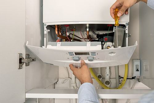 Heating technician repairing a residential boiler in Galt