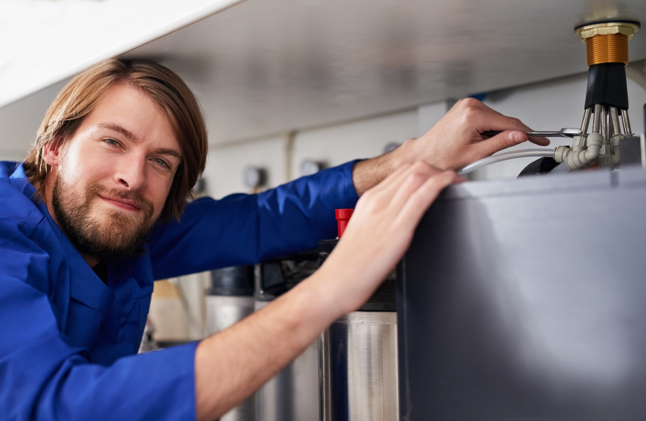 Technician servicing a residential water heater tank in Galt